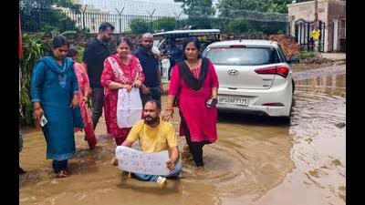 लखनऊ: 'लापता' सड़क को लेकर नगर निगम अधिकारियों को शर्मिंदा करने के लिए निवासियों ने पानी भरी सड़क को एक मंच में बदल दिया 4 Residents stand in stagnant water holding placard 1784660619551